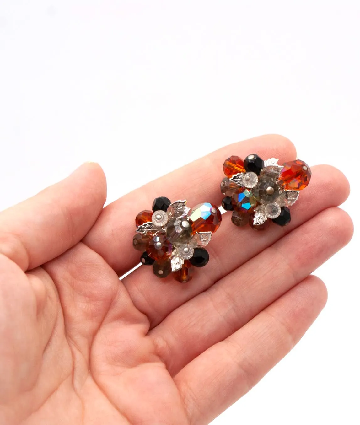 Vendôme Orange and Black Beaded Cluster Clip on Earrings held in a hand
