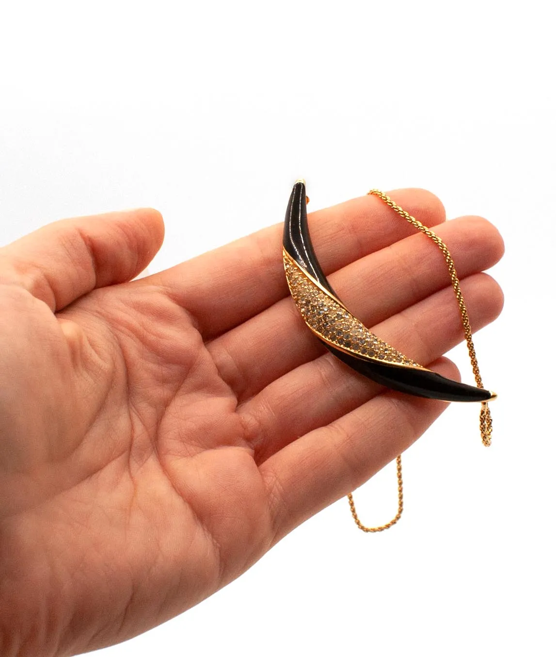 Black enamel and rhinestone necklace from Christian Dior held in a hand