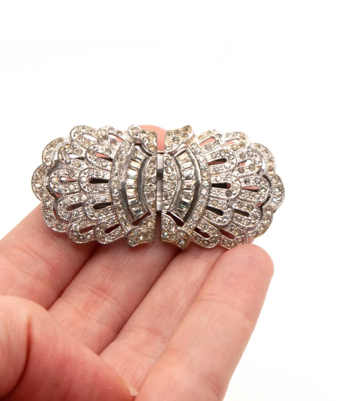 Curved edge Art Deco duo rhinestone dress clip brooch sitting on a hand