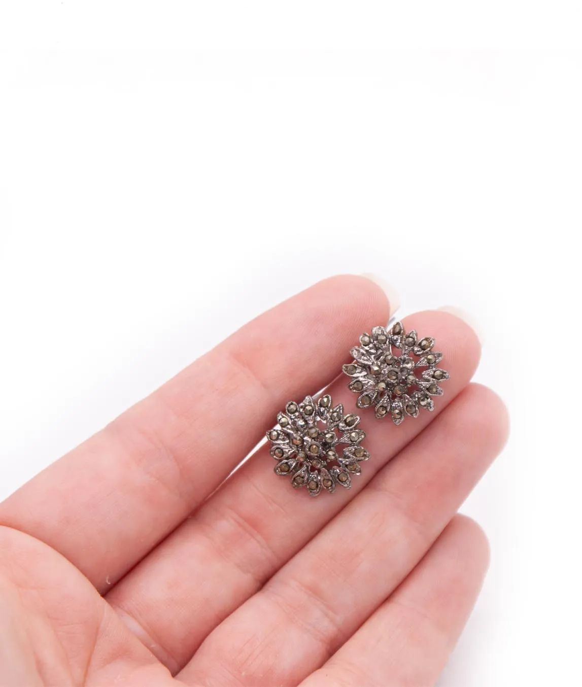 Vintage floral silver-tone marcasite chip clip-on earrings in a hand